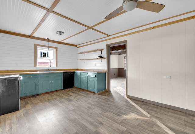 kitchen featuring light wood-type flooring, ceiling fan, sink, black dishwasher, and wood walls