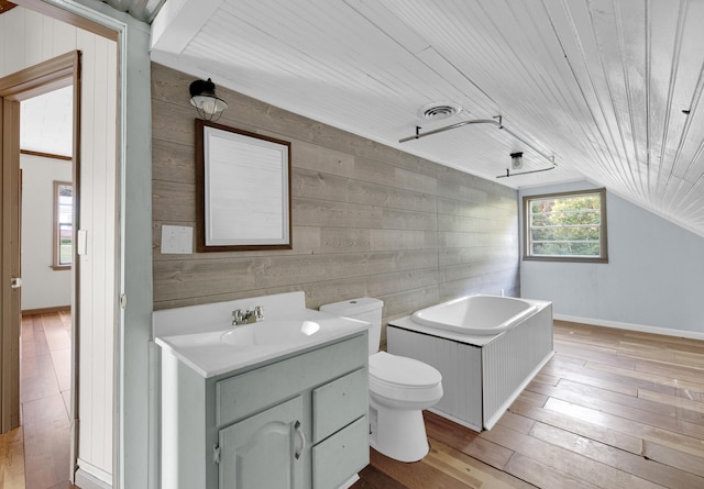 bathroom featuring vanity, wood-type flooring, wooden walls, and vaulted ceiling