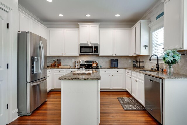 kitchen with a center island, white cabinets, sink, appliances with stainless steel finishes, and light stone counters