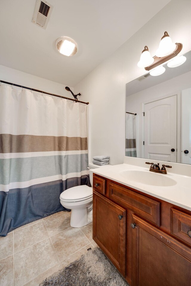 bathroom with tile patterned flooring, vanity, toilet, and curtained shower