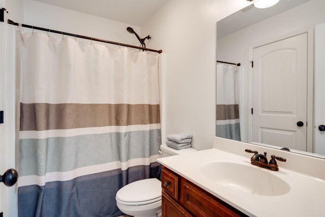 bathroom with curtained shower, vanity, and toilet