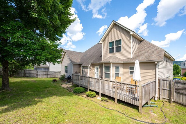 back of house featuring a lawn and a wooden deck