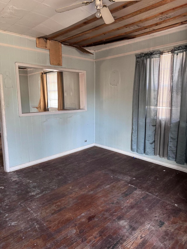 empty room with ceiling fan, wood walls, and dark hardwood / wood-style floors