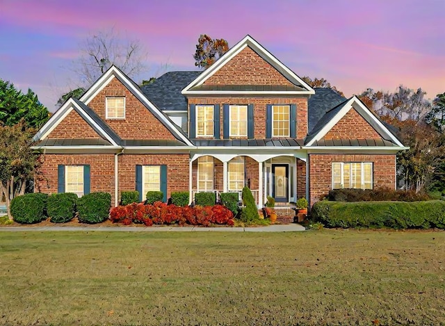 289 Magnolia Pl, Ringgold, GA 30736 - view of front facade featuring a standing seam roof, a yard, brick siding, covered porch, and roof with shingles