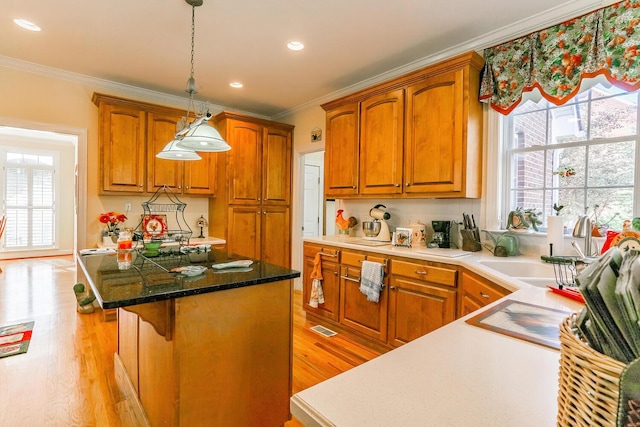 kitchen featuring a center island, hanging light fixtures, a kitchen breakfast bar, light hardwood / wood-style flooring, and ornamental molding