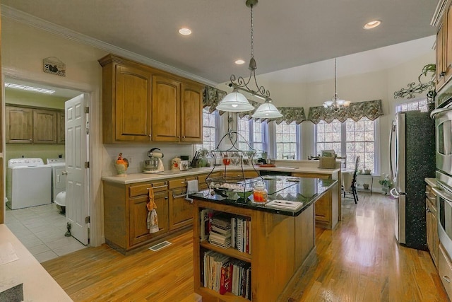 kitchen with black electric cooktop, pendant lighting, separate washer and dryer, a center island, and light hardwood / wood-style floors