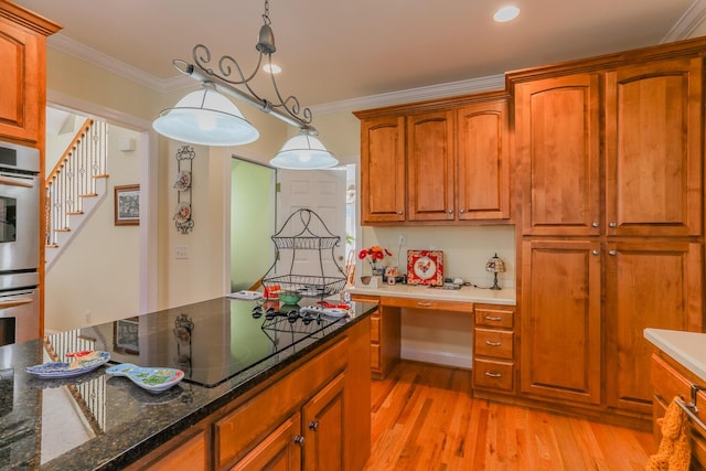 kitchen featuring black stovetop, dark stone countertops, light wood-type flooring, ornamental molding, and decorative light fixtures