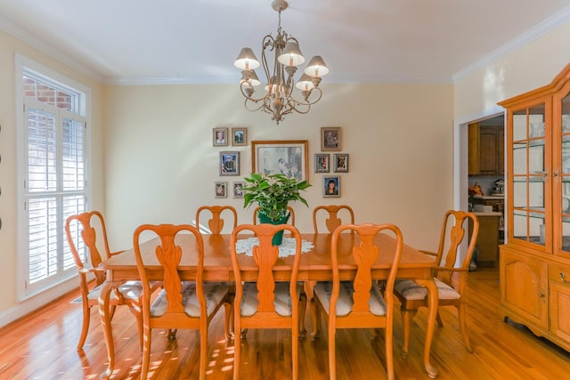 dining area featuring crown molding, a healthy amount of sunlight, light wood-type flooring, and an inviting chandelier