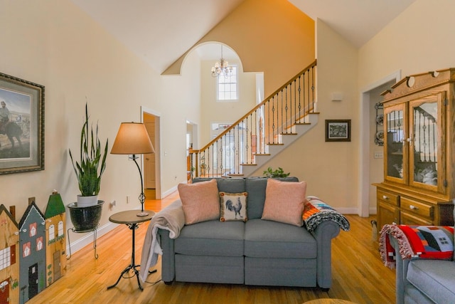 living room featuring wood-type flooring, high vaulted ceiling, and a chandelier