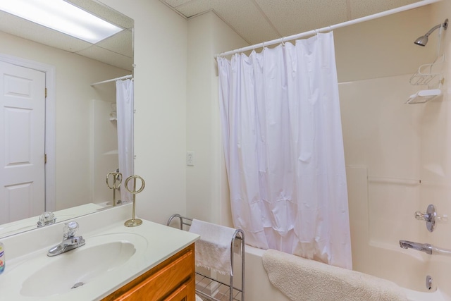 bathroom with shower / bath combo with shower curtain, a drop ceiling, and vanity