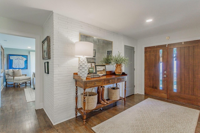 entrance foyer with french doors, dark hardwood / wood-style floors, and brick wall