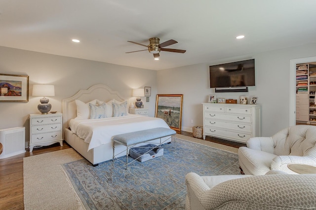 bedroom featuring dark hardwood / wood-style floors, ceiling fan, a walk in closet, and a closet