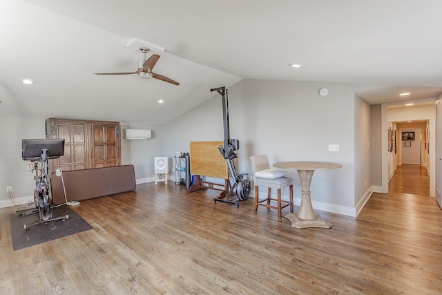 exercise room with an AC wall unit, ceiling fan, hardwood / wood-style floors, and lofted ceiling