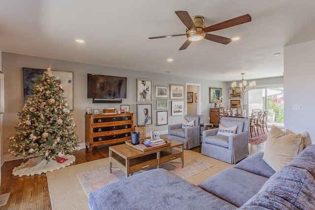 living room featuring ceiling fan with notable chandelier and hardwood / wood-style flooring