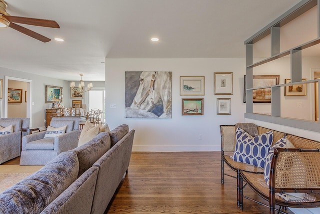 living room with dark hardwood / wood-style flooring and ceiling fan with notable chandelier