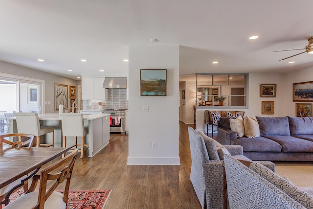 living room featuring ceiling fan, sink, and wood-type flooring