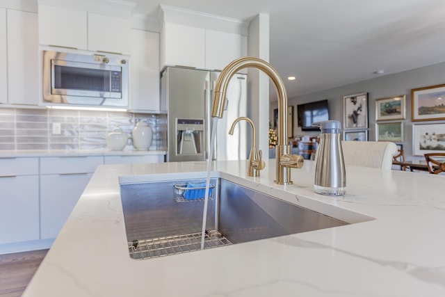 kitchen featuring light stone countertops, decorative backsplash, stainless steel appliances, and sink