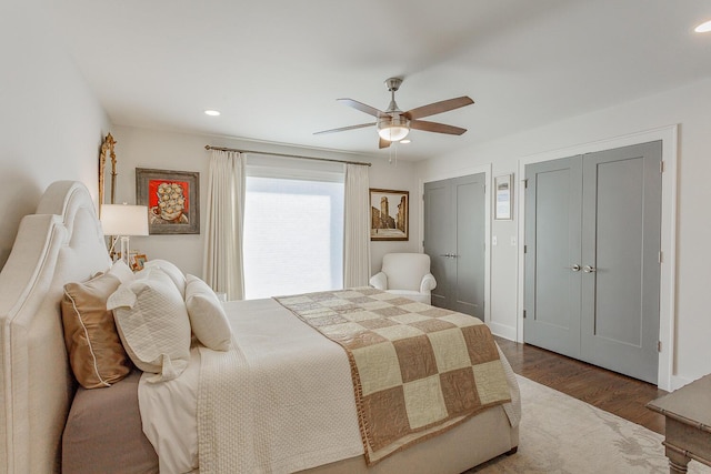 bedroom featuring ceiling fan, dark hardwood / wood-style floors, and two closets