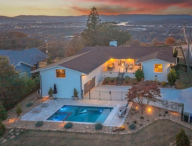 pool at dusk featuring a mountain view and a patio