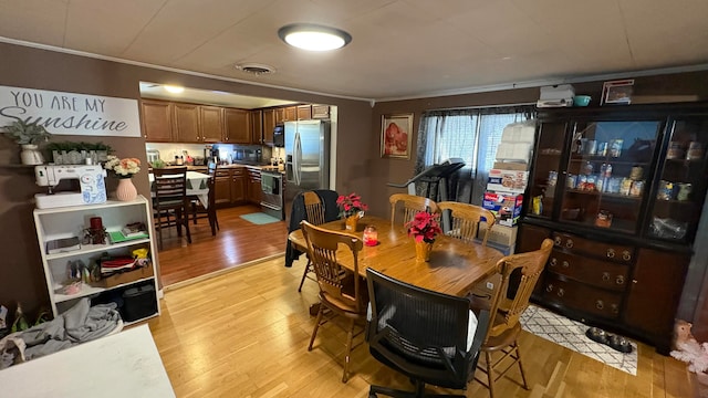 dining space with light hardwood / wood-style floors and ornamental molding