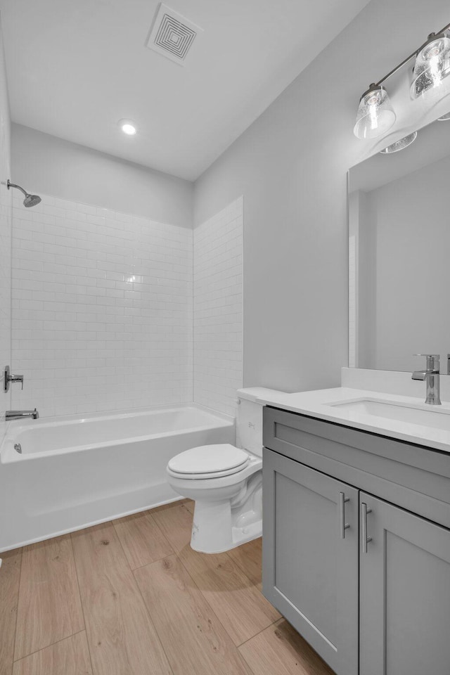 full bathroom featuring tiled shower / bath, toilet, vanity, and hardwood / wood-style flooring