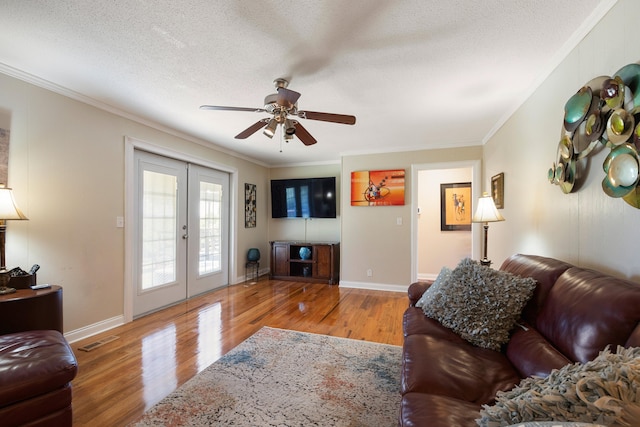 living room featuring french doors, ornamental molding, a textured ceiling, and light hardwood / wood-style flooring