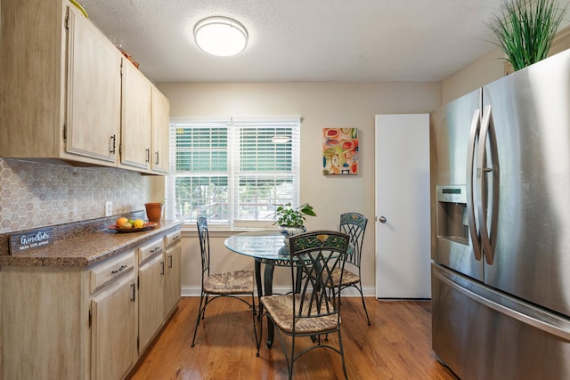 kitchen featuring light hardwood / wood-style flooring, decorative backsplash, stainless steel fridge, a textured ceiling, and light brown cabinetry