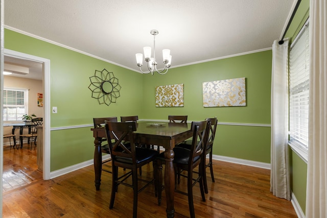 dining room featuring a textured ceiling, a notable chandelier, crown molding, and dark wood-type flooring