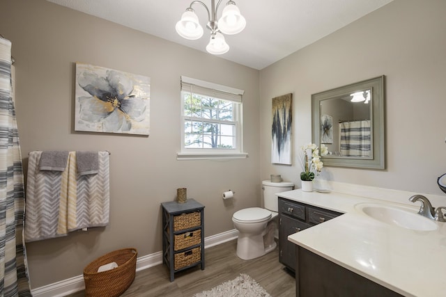 bathroom featuring toilet, vanity, wood-type flooring, and an inviting chandelier