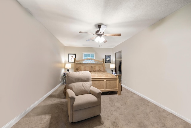 bedroom with ceiling fan, light carpet, and a textured ceiling