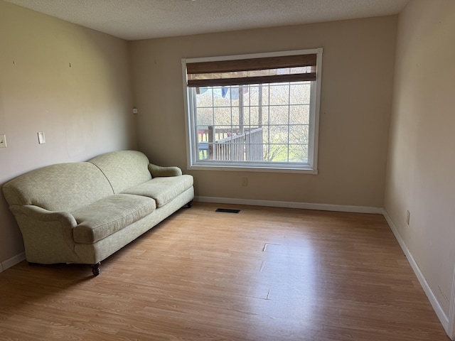 sitting room with a textured ceiling and light hardwood / wood-style flooring