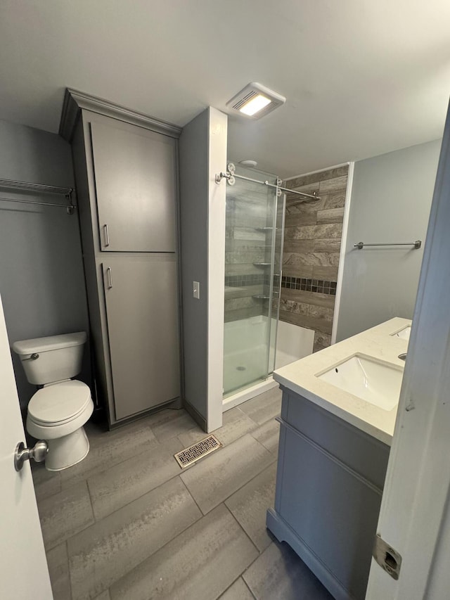 bathroom with toilet, a shower with shower door, and vanity