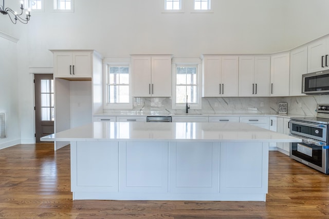 kitchen with white cabinetry, stainless steel appliances, dark hardwood / wood-style floors, pendant lighting, and a kitchen island