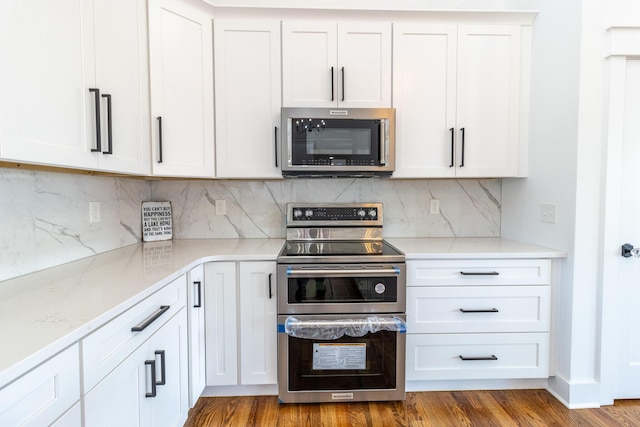 kitchen with white cabinets, wood-type flooring, and appliances with stainless steel finishes