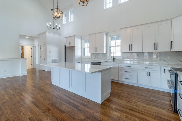 kitchen with white cabinetry, sink, a high ceiling, dark hardwood / wood-style flooring, and a kitchen island