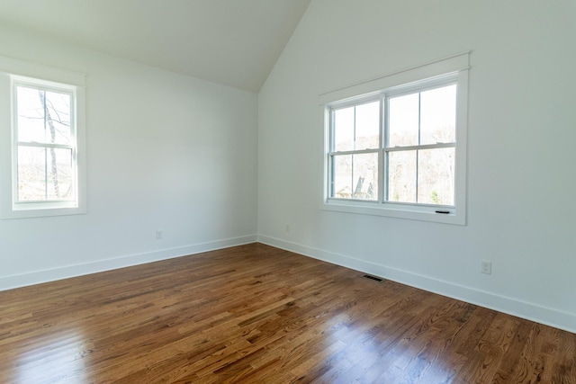 spare room with dark wood-type flooring and vaulted ceiling