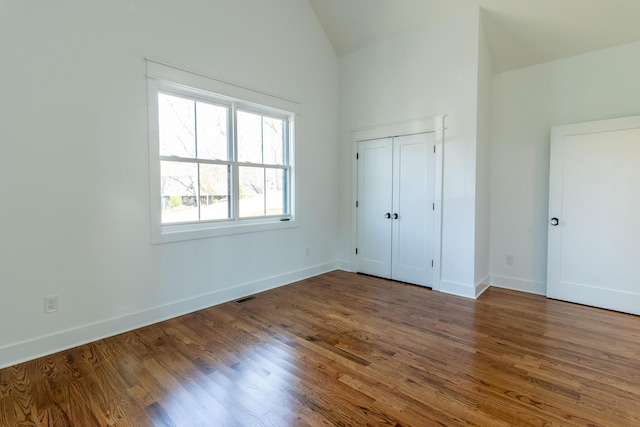 unfurnished bedroom with dark hardwood / wood-style floors, a closet, and vaulted ceiling