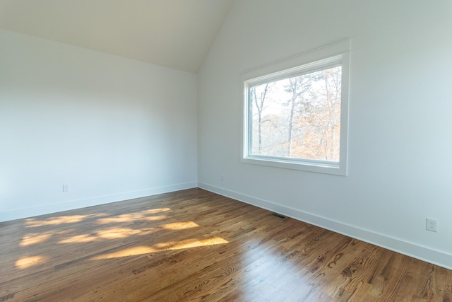 unfurnished room featuring lofted ceiling and dark wood-type flooring