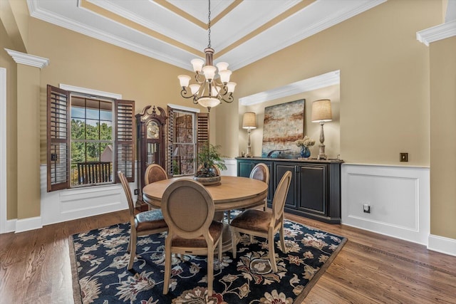 dining space with dark hardwood / wood-style flooring, a notable chandelier, ornamental molding, and a raised ceiling