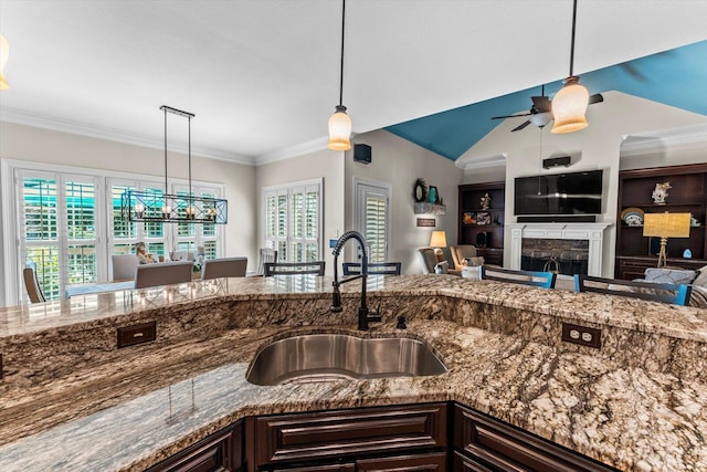 kitchen featuring sink, decorative light fixtures, dark brown cabinets, and stone countertops