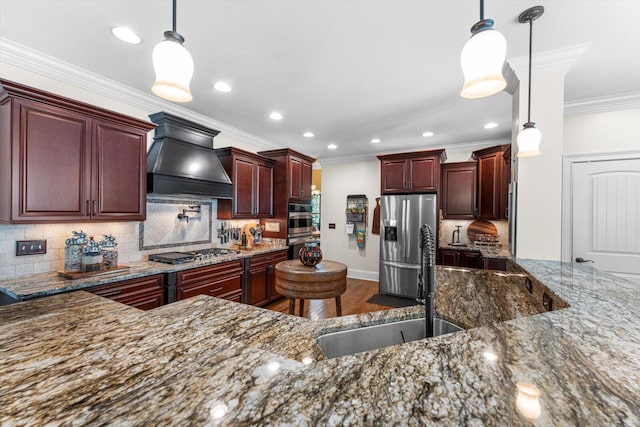 kitchen featuring premium range hood, sink, crown molding, decorative light fixtures, and appliances with stainless steel finishes