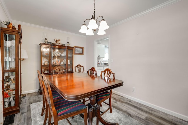 dining area with a chandelier, hardwood / wood-style floors, and ornamental molding