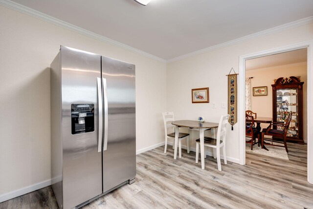 kitchen featuring stainless steel fridge, light hardwood / wood-style floors, and crown molding