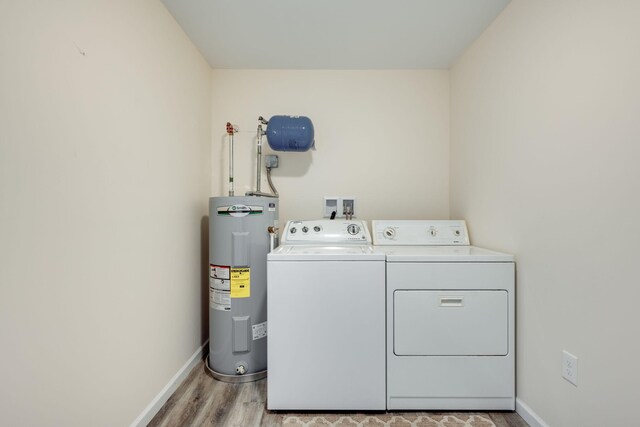 clothes washing area featuring washing machine and clothes dryer, light wood-type flooring, and water heater