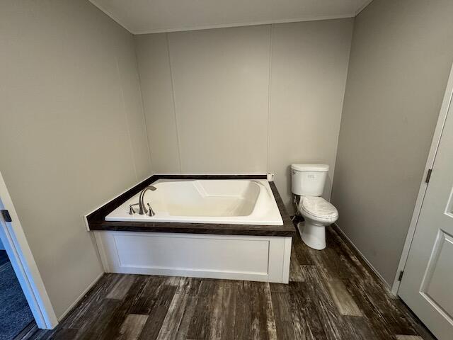 bathroom with wood-type flooring, toilet, and a tub to relax in