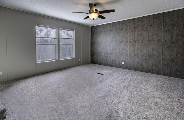 carpeted empty room featuring ceiling fan and a textured ceiling