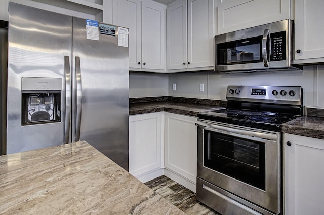 kitchen with stainless steel appliances, white cabinetry, and light stone countertops