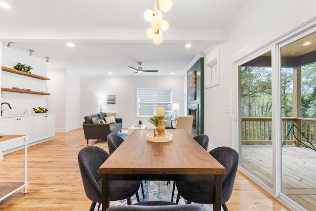 dining area with ceiling fan, sink, light wood-type flooring, and crown molding