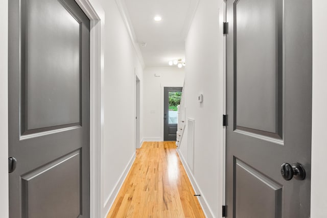 corridor with light wood-type flooring and ornamental molding