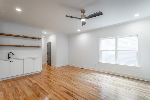 empty room with ceiling fan, light hardwood / wood-style floors, ornamental molding, and sink